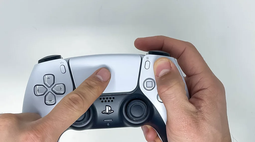 Persoon die de Sony PS5 DualSense draadloze controller in beide handen vasthoudt en een wit touchpad gebruikt op een witte achtergrond