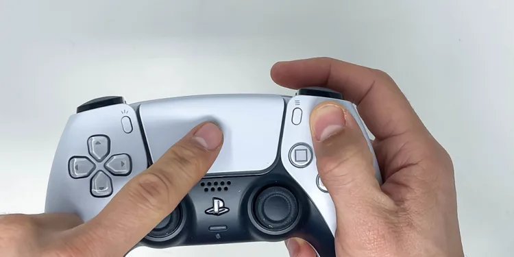 personne tenant la manette sans fil Sony PS5 Dualsense dans les deux mains et utilisant le pavé tactile blanc sur fond blanc