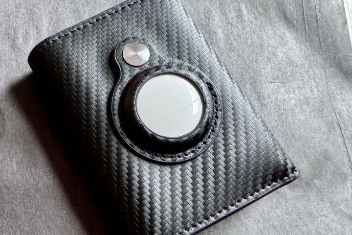 An Apple AirTag placed inside a black wallet.