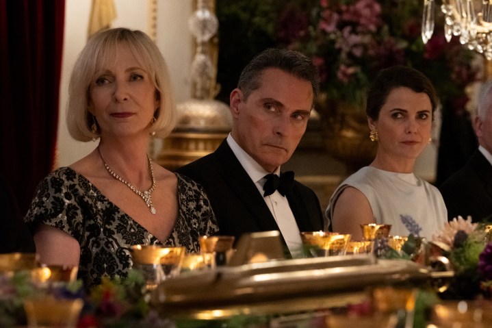 A man sits between two women at a dinner table.