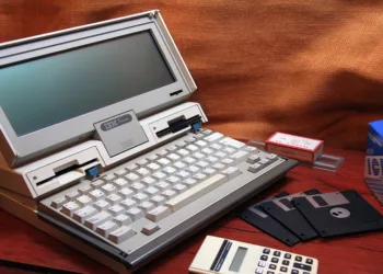 Woman in yellow holding up a red floppy disk at her desk