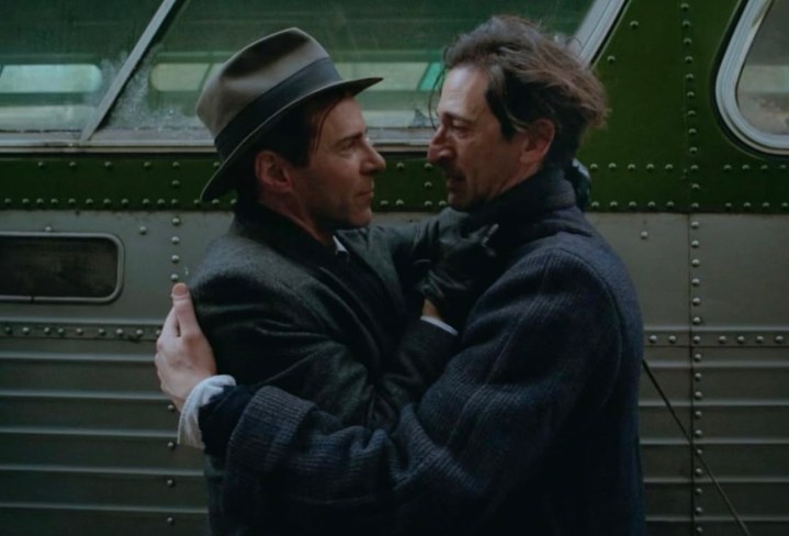 Two men embracing outside a bus.