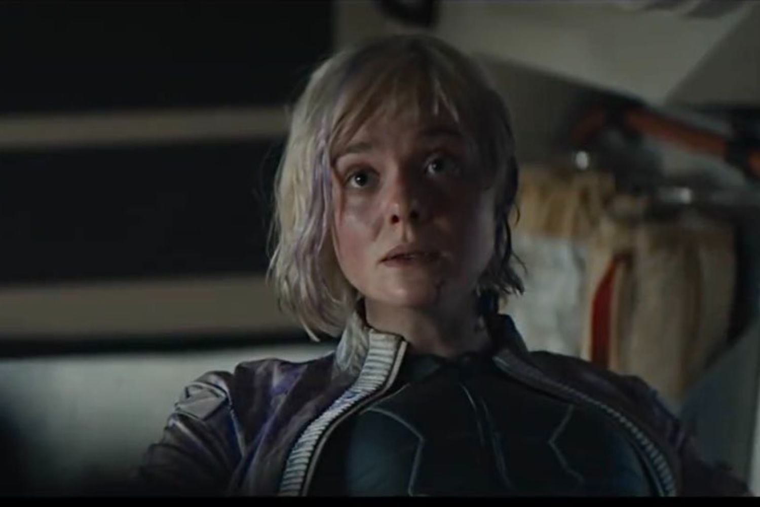 Elle Fanning seated and looking at something.