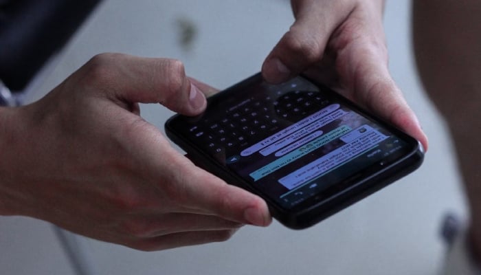 A man using WhatsApp on his phone.