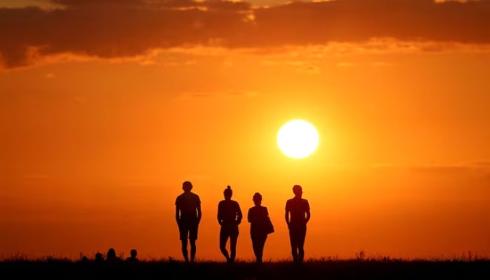 People silhouetted against the sunset on Drachenberg in Berlin, Germany, August 19, 2019. — Reuters