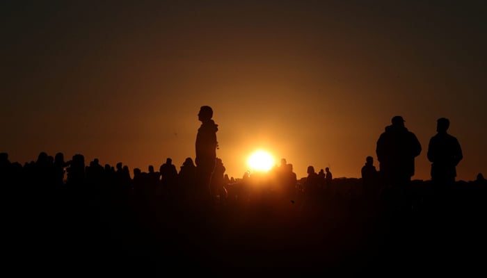 Celebrators observe the sunset on the eve of the summer solstice at the Stonehenge stone circle in Amesbury, England, June 20. — Reuters