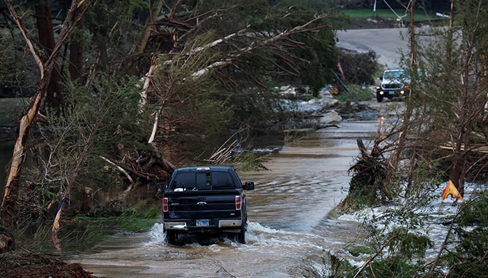 A vehicle navigates through a flooded road in Hunt, Texas, on July 6, 2025. — Reuters