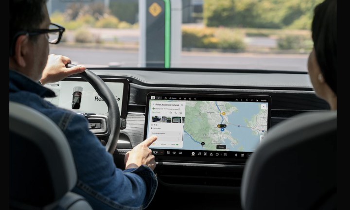 A man sitting in the driver's seat, interacting with Google Maps on a central touchscreen