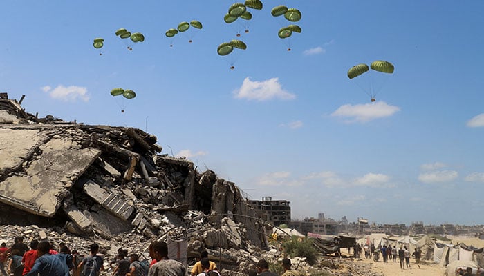 Palestinians rushing towards parachutes loaded with aid in northern Gaza, August 7, 2025. — Reuters