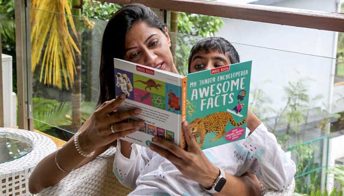 Vidushi Malhotra, a pollution refugee and founder of an education advisory organization, reading a children's book to her son at their home in Goa on September 27, 2025. — AFP