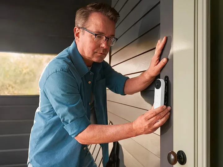 A person installing a wired Google Nest Doorbell near their front door
