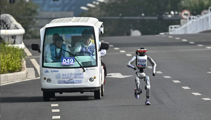 A robot alongside its engineers during the Beijing E-Town Half Marathon, April 19, 2026. — AFP