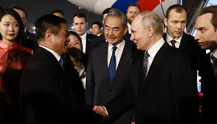 In this pool photograph distributed by the Russian state agency Sputnik, Putin is greeted by Chinese Foreign Minister Wang Yi and other officials at Beijing Capital Airport late on May 19, 2026. — AFP